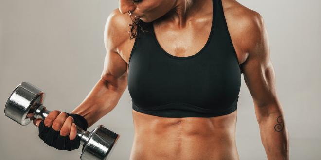 a strong, fit woman lifting small weights during her workout